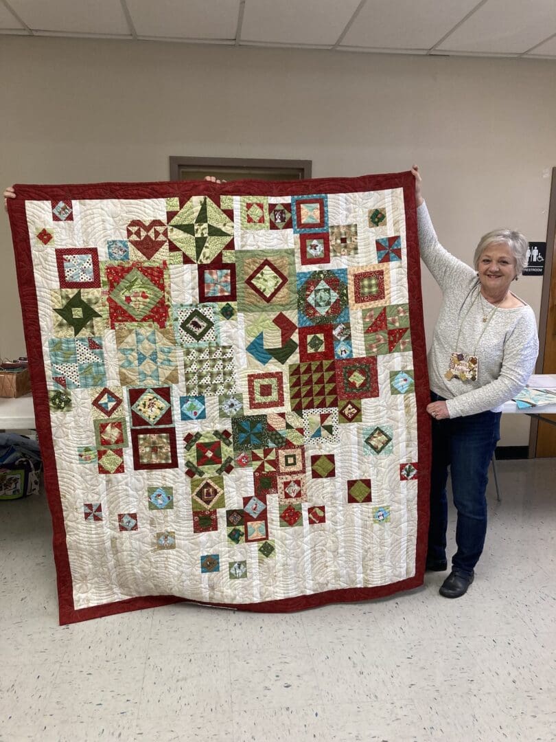 A woman showing a quilt